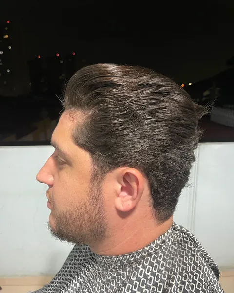 Cabelo penteado para trás Cliente de perfil à noite com o cabelo penteado para trás e barba curta, de capa estampada